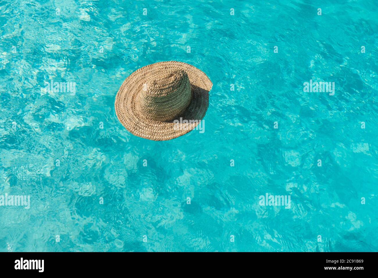 Ein Strohhut schwimmt in einem blauen Pool, Spanien. Stockfoto