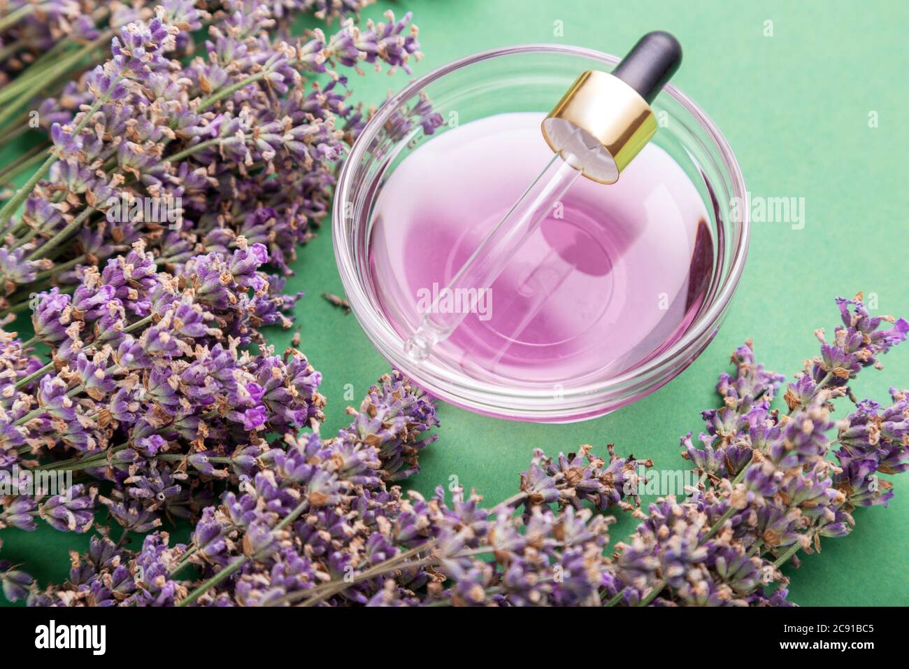 Lavendelöl Flüssigkeit mit Pipette Pipette frische Lavendelblüten auf grünem Hintergrund. Natürliche Körper Haut Haarpflege Bad Produkte. Aromatherapie Stockfoto