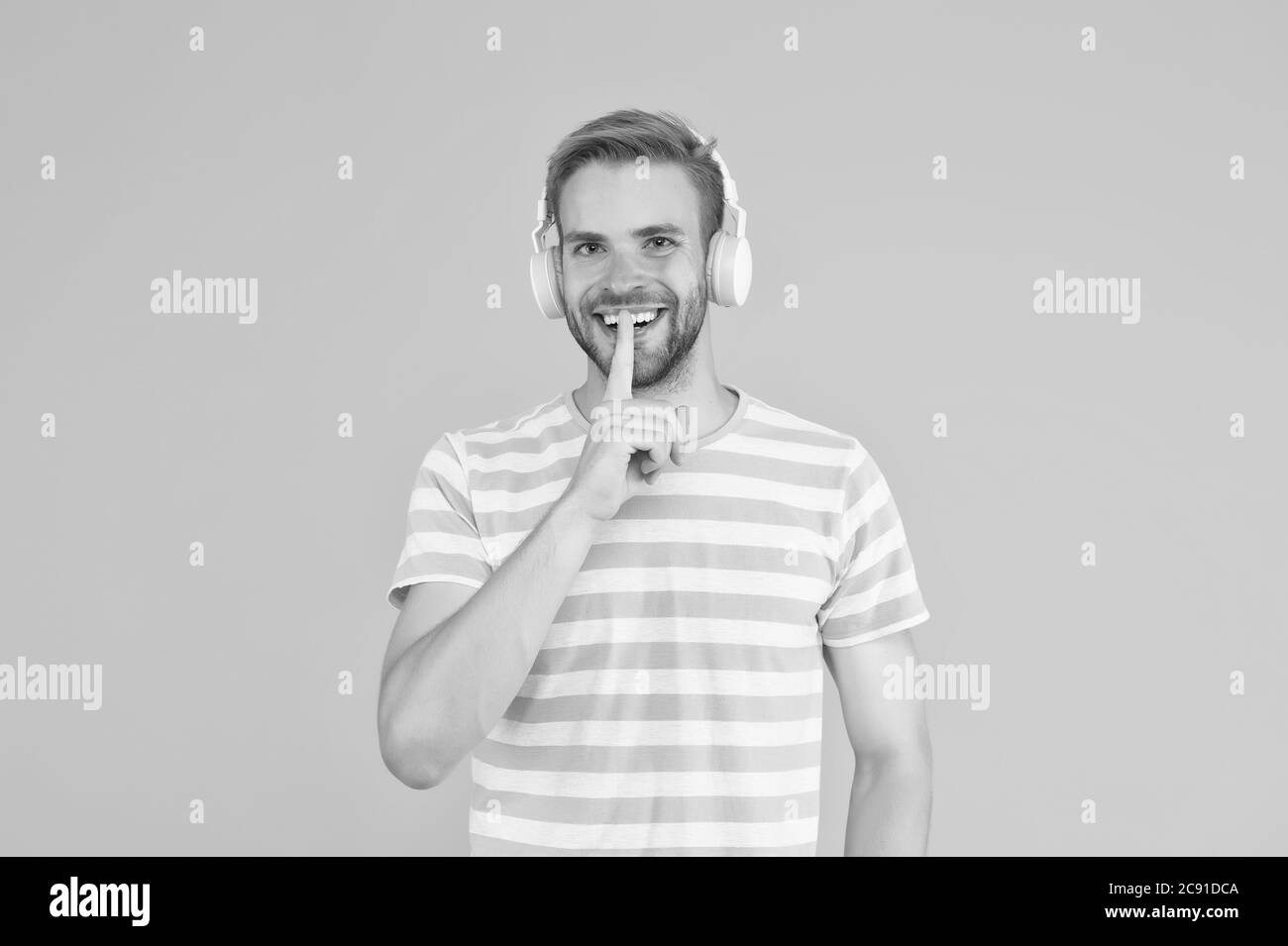 In der Musik ist Stille wichtiger als Klang. Glücklicher Mann machen geheime Geste. Guy hören Tonspur in Kopfhörern. Sound- und Musiktechnologie. Stereo-Sound. Bitte ruhig, während Musik abgespielt wird. Stockfoto