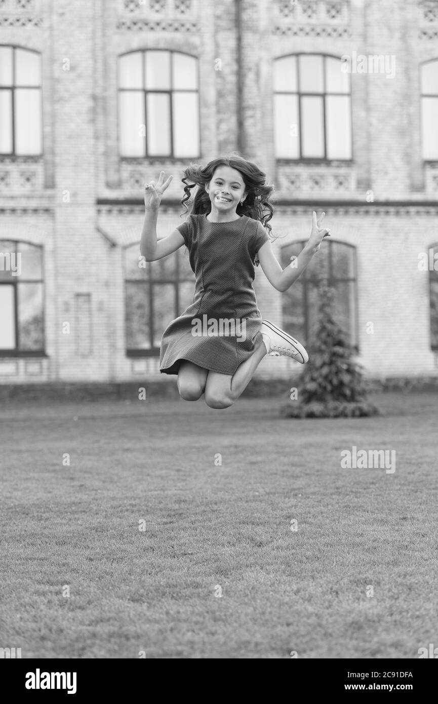 Fühlen Sie sich frei. Sprung des Glücks. Kleines Mädchen springen auf grünem Gras. Voller Energie. Aktive Mädchen fühlen Freiheit. Spaß und Entspannung. Unbeschwertes Kind im Sommerurlaub. Teenager in rosa Kleid. Mädchen springen im Freien. Stockfoto