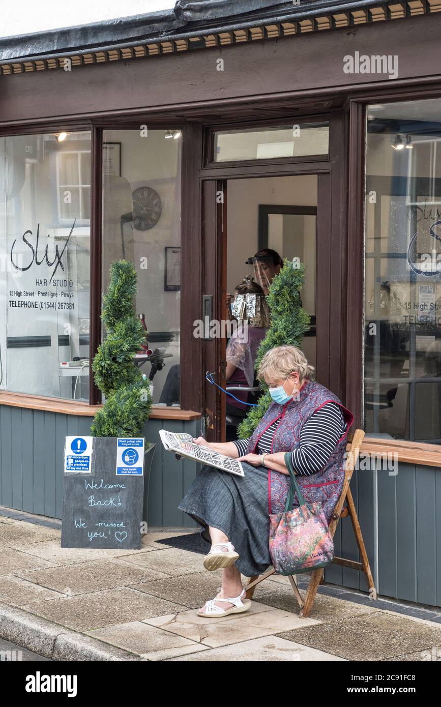 Ein Kunde wartet auf Termine außerhalb von Slix, dem lokalen Friseursalon, da er nach monatelanger Sperre in Presteigne, Powys, Wales, Großbritannien wieder eröffnet wird Stockfoto