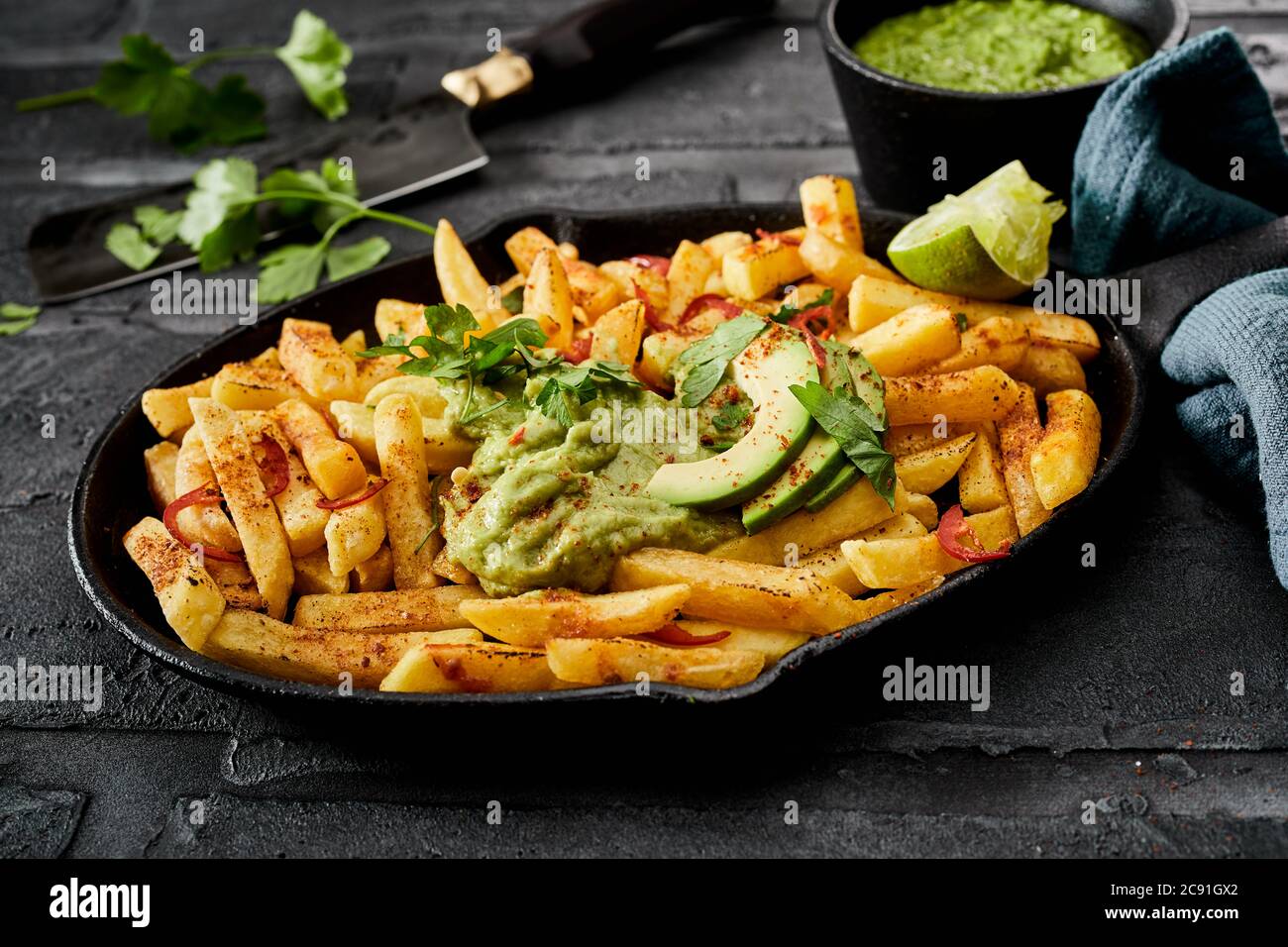 Servieren Sie knusprige goldene Kartoffelchips mit Chili und Gewürzen, garniert mit mexikanischer Guacamole-Sauce und frischer Avocado-Birne aus nächster Nähe für ein Menü Stockfoto