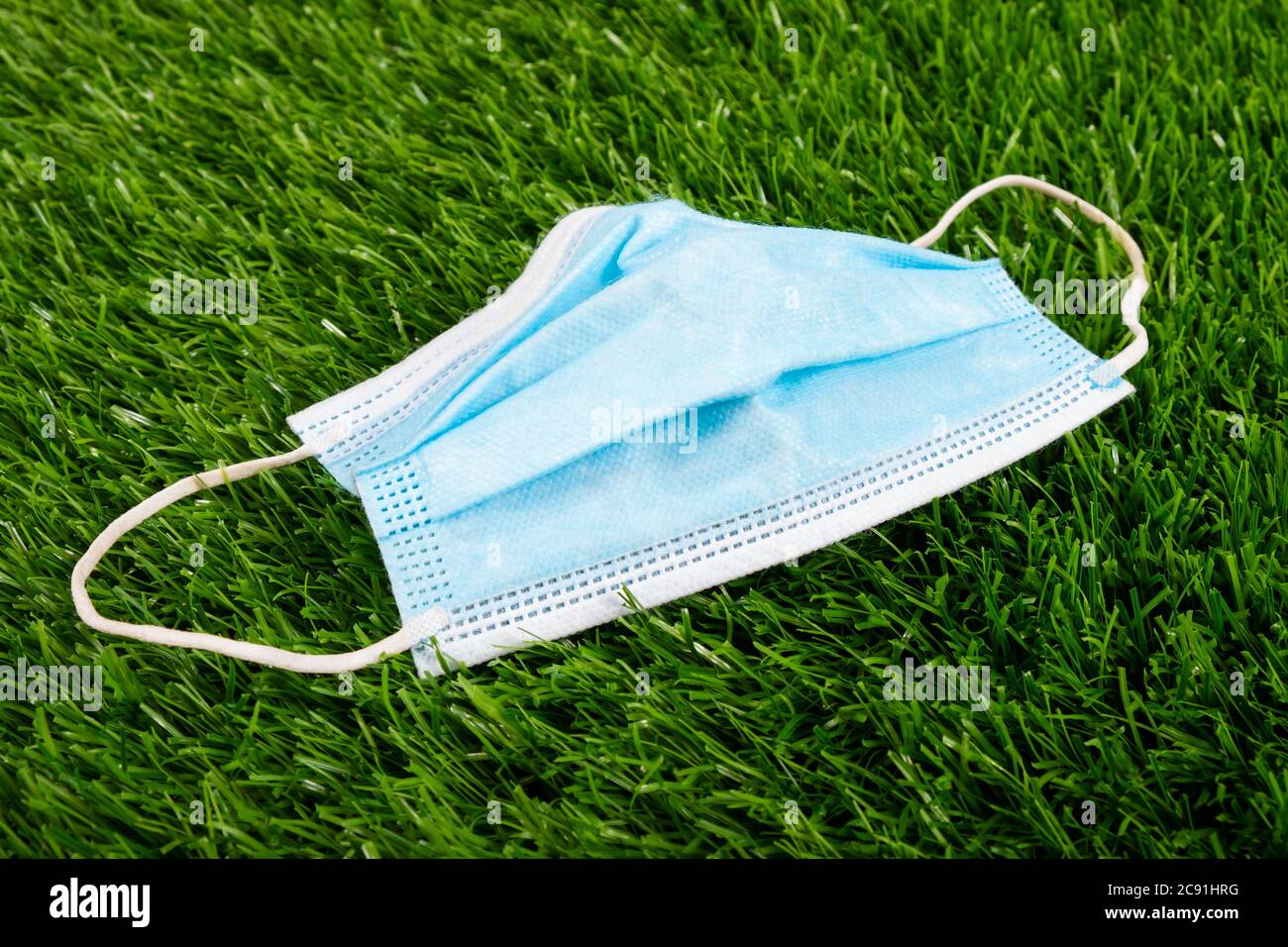 Medizinische blaue Maske auf grünem Gras Nahaufnahme. Verschmutzung der Umwelt während der Quarantäne wegen der Pandemie covid-19. Stockfoto