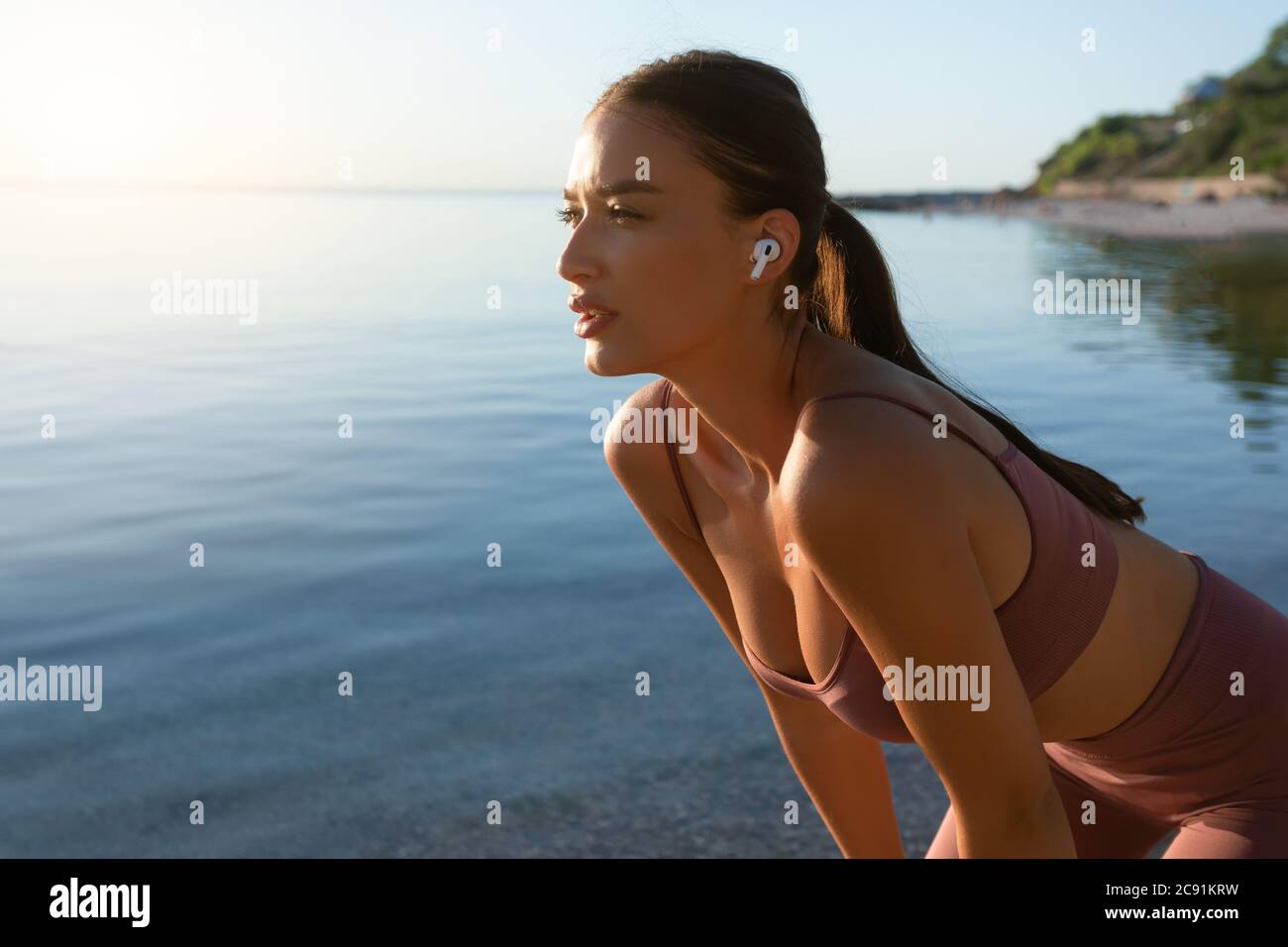 Junges Mädchen, das Pause nach dem Laufen am Strand Stockfoto
