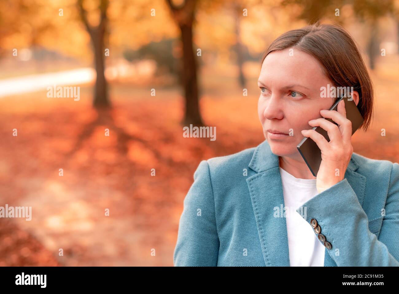 Geschäftsfrau Gespräch am Handy im Herbst Park, Portrait von Erwachsenen kaukasischen business Person während des Gesprächs Stockfoto