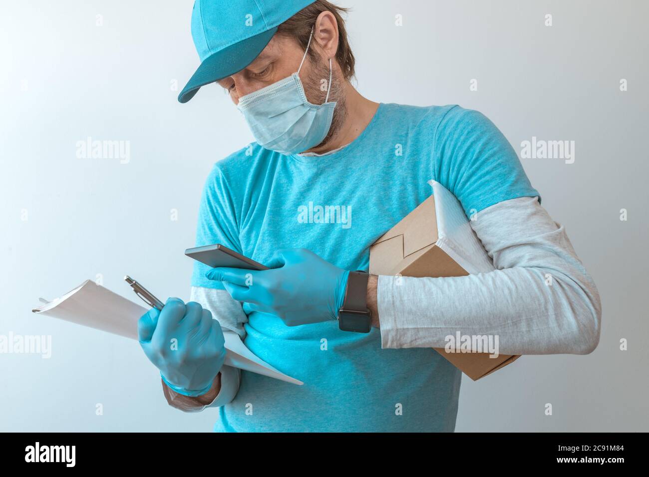 Lieferung Mann mit Schutzkleidung mit Smartphone mit Schutzhandschuhen während Virusinfektion Pandemie, selektive Fokussierung Stockfoto