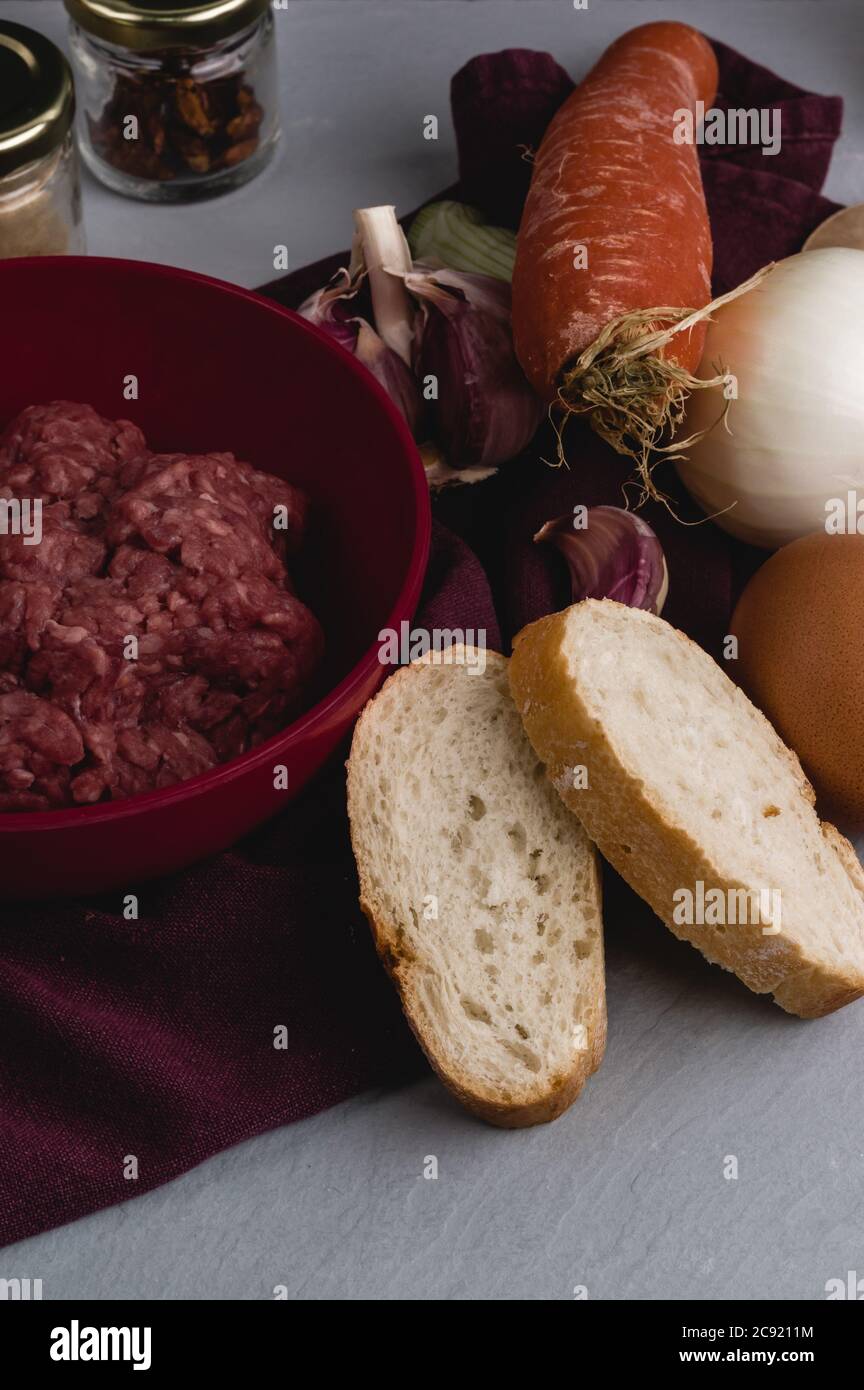 Verticcal Nahaufnahme von Zutaten für die Zubereitung von Fleischbällchen auf einem Weißer Küchentisch Stockfoto