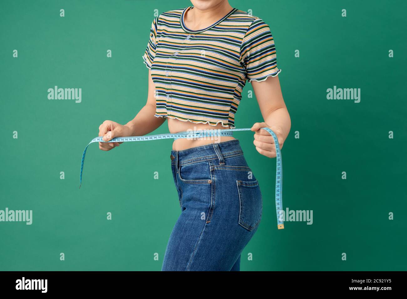 Nahaufnahme junge Frau Messung ihre Taille mit Band Maß über grünem Hintergrund. Stockfoto