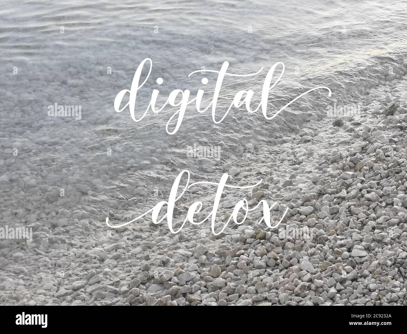 Digitales Detox-Konzept. Kieselsteine am Meer, diagonaler Wasserrand. Ruhiger natürlicher Hintergrund mit Text Digital Detox. Stockfoto
