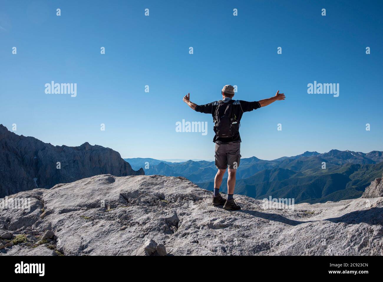 Ein Mann steht mit den Armen aus, um die Schönheit zu umarmen Der Berge Stockfoto