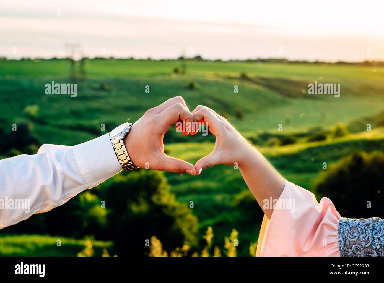 Der Kerl und das Mädchen machen aus den Fingern eine Herzform als Symbol der Liebe Stockfoto