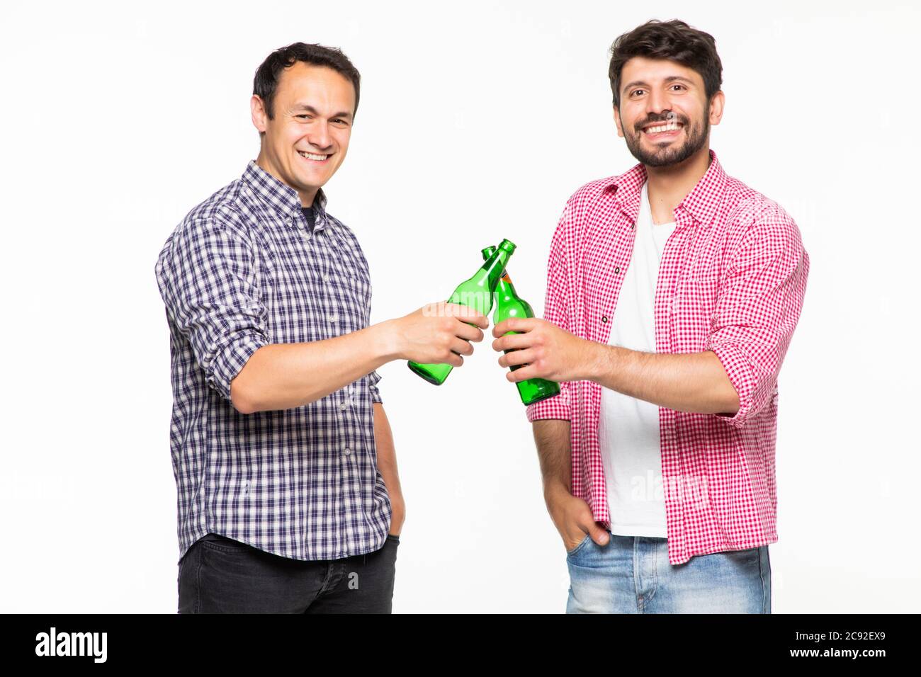 Portrait von zwei aufgeregten jungen Männern besten Freunden Toasting mit Bierflaschen auf weißem Hintergrund Stockfoto