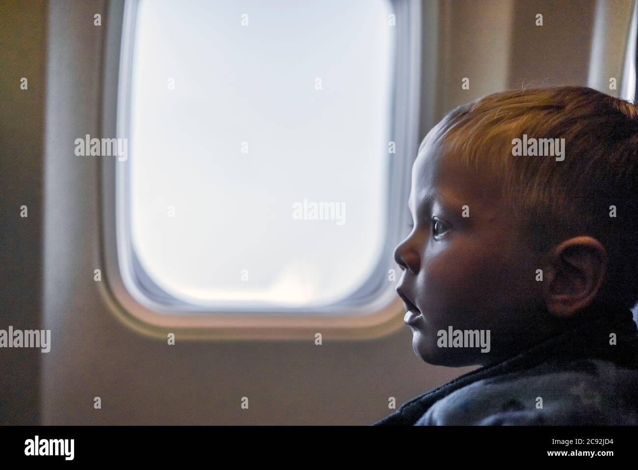 Ernst kleiner Junge sitzt neben dem Fenster im Flugzeug Stockfoto