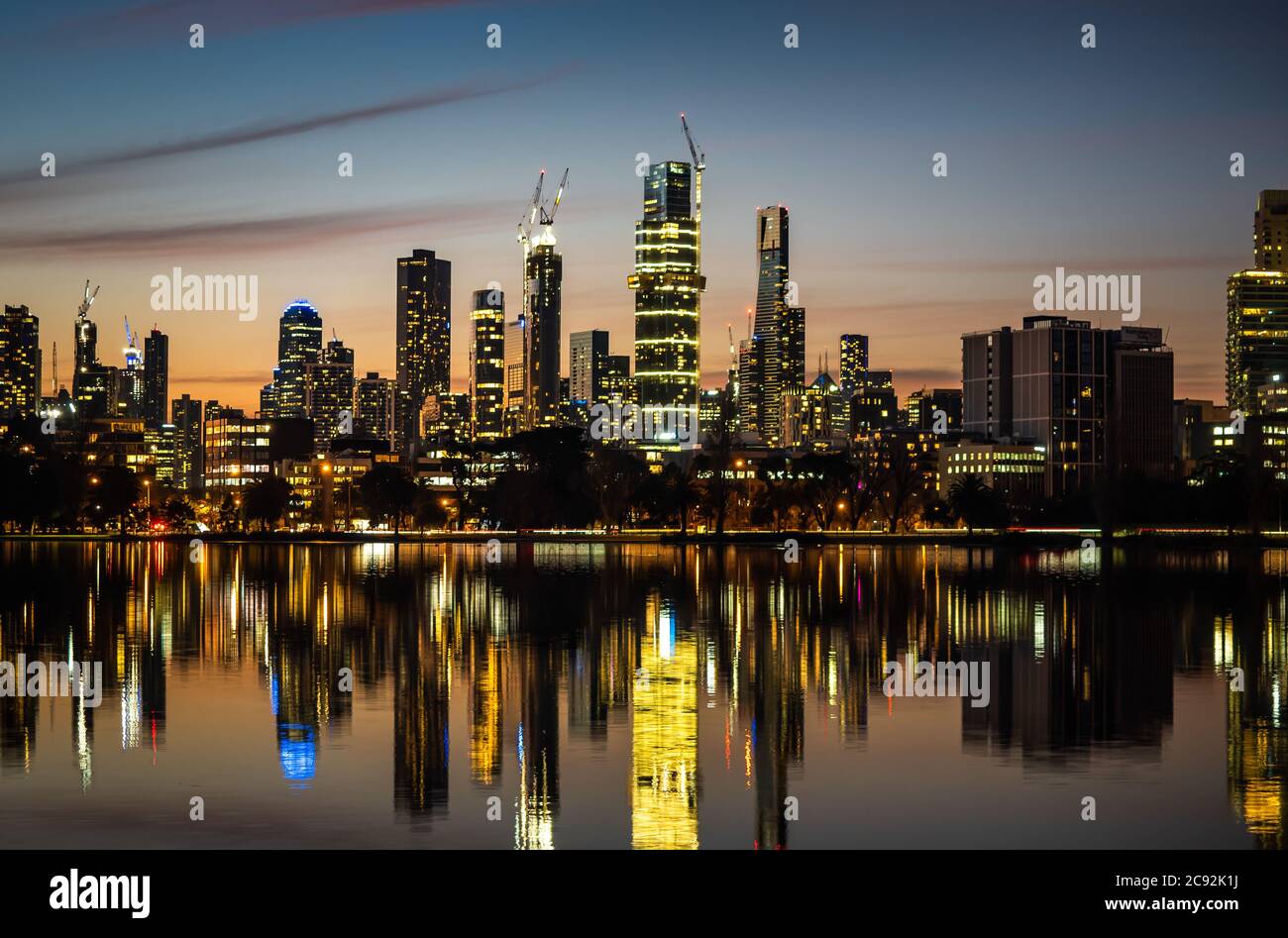 Die Spiegelungen der skyline von melbourne in der Abenddämmerung im stillen Wasser des albert Park Lake Stockfoto