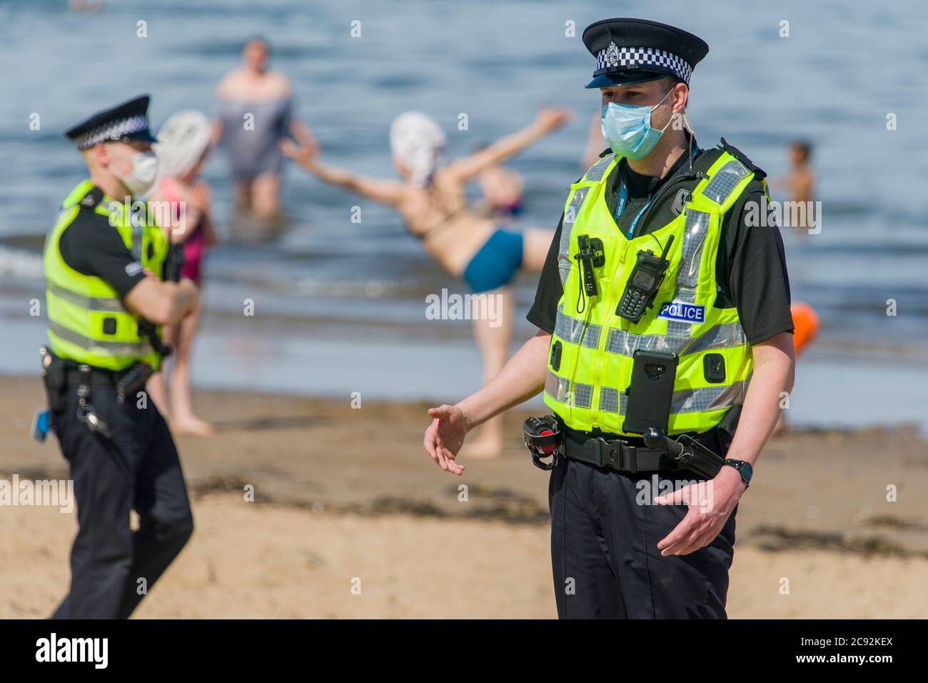 Maskierte Polizisten fordern die Öffentlichkeit auf, heute am Portobello-Strand in Edinburgh die Sonne von bis zu 21 Grad zu lassen. Schottland befindet sich in der 9. Woche der Sperre aufgrund des Covid-19-Ausbruchs. Kredit: Euan Cherry Stockfoto