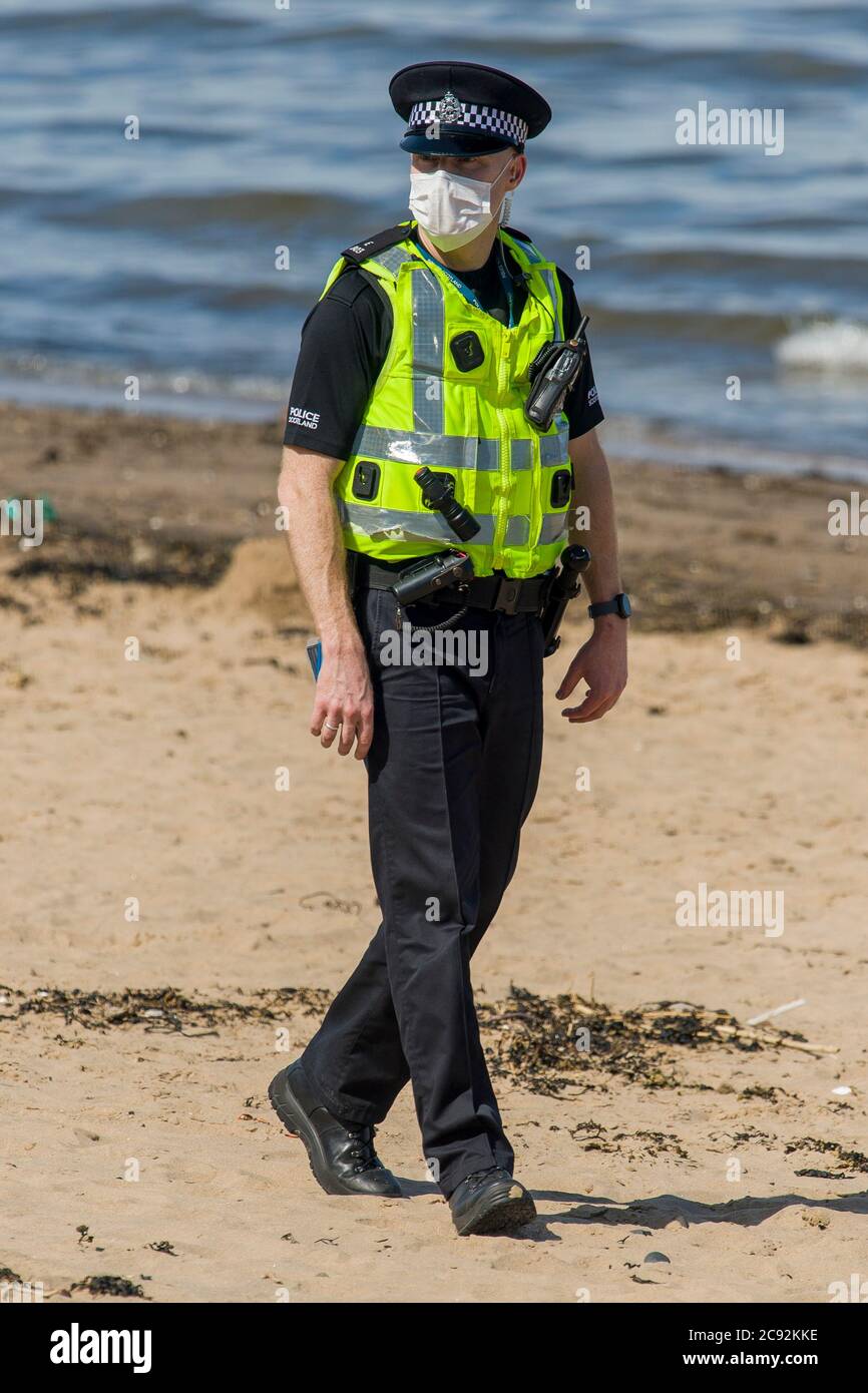 Maskierte Polizisten fordern die Öffentlichkeit auf, heute am Portobello-Strand in Edinburgh die Sonne von bis zu 21 Grad zu lassen. Schottland befindet sich in der 9. Woche der Sperre aufgrund des Covid-19-Ausbruchs. Kredit: Euan Cherry Stockfoto