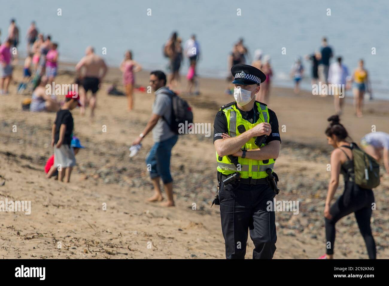 Maskierte Polizisten fordern die Öffentlichkeit auf, heute am Portobello-Strand in Edinburgh die Sonne von bis zu 21 Grad zu lassen. Schottland befindet sich in der 9. Woche der Sperre aufgrund des Covid-19-Ausbruchs. Kredit: Euan Cherry Stockfoto