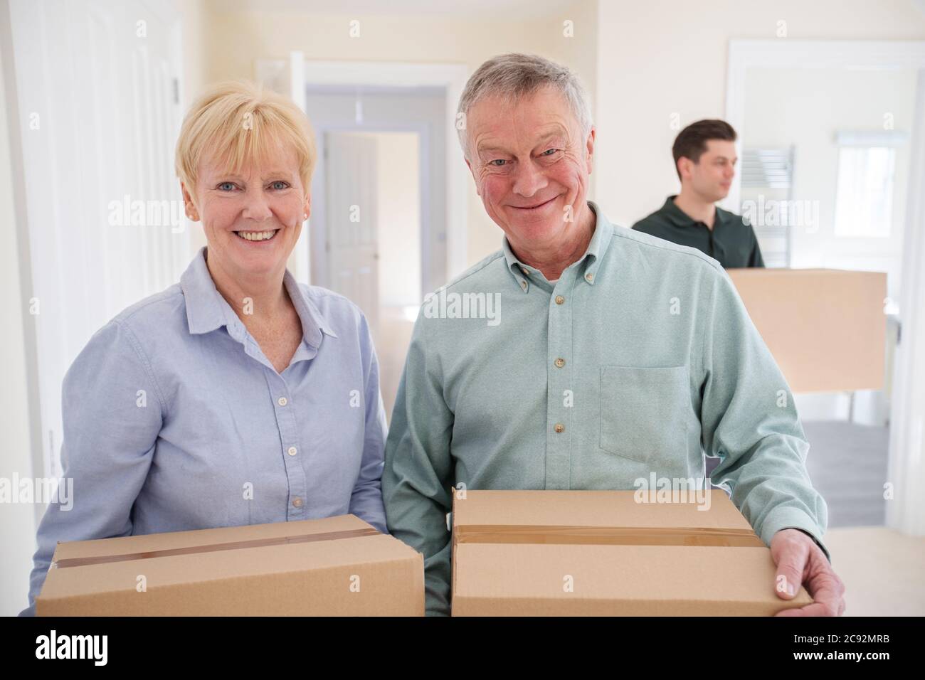 Porträt Des Älteren Paares Downsizing Im Ruhestand Tragen Von Kisten In Neue Heimat Am Umzug Tag Mit Entfernung Mann Hilft Stockfoto