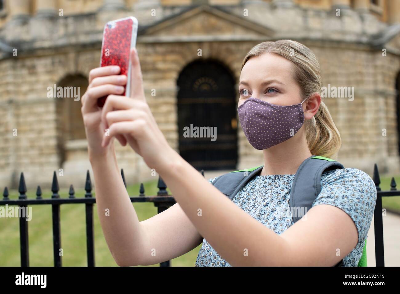 Weibliche Touristen im Urlaub tragen Gesichtsmaske während Covid-19 Pandemie Foto auf Handy in Oxford UK Stockfoto