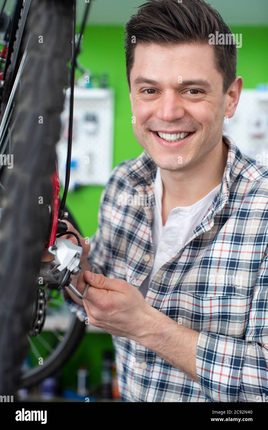 Porträt Des Männlichen Kleinunternehmers Reparatur Der Zahnräder Im Fahrradreparatur-Shop Stockfoto