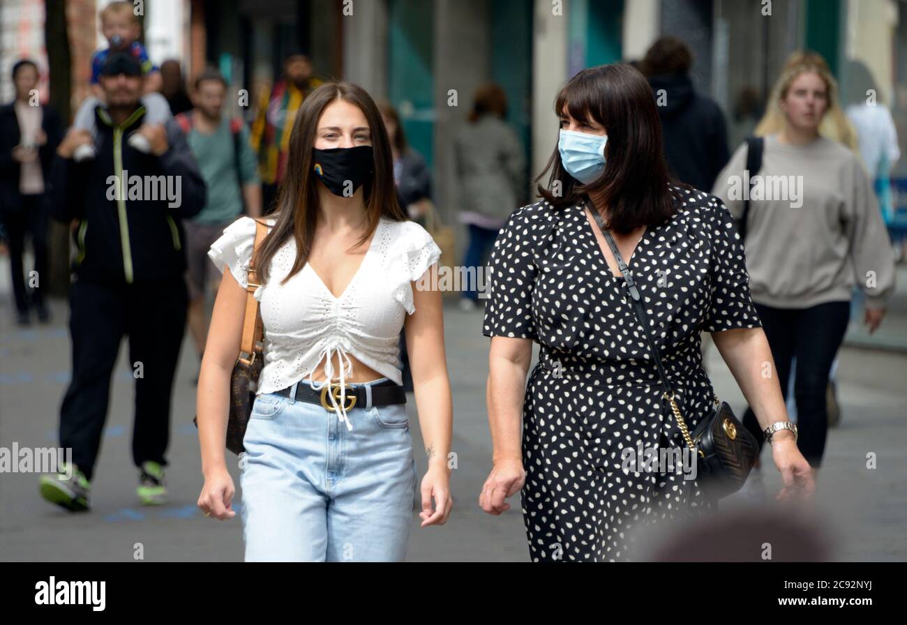 Zwei junge Frauen, die auf der Straße maskiert sind, nach der Sperre in Nottingham. Stockfoto