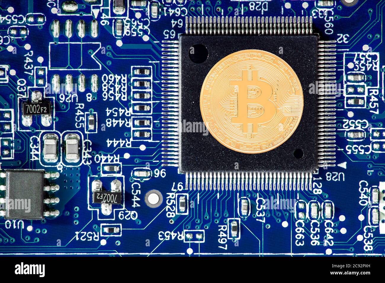 Der Bitcoin liegt auf der cpu, die Goldmünze der Kryptowährung auf dem Mikroprozessor der blauen Leiterplatte ist eine Draufsicht, niemand. Stockfoto