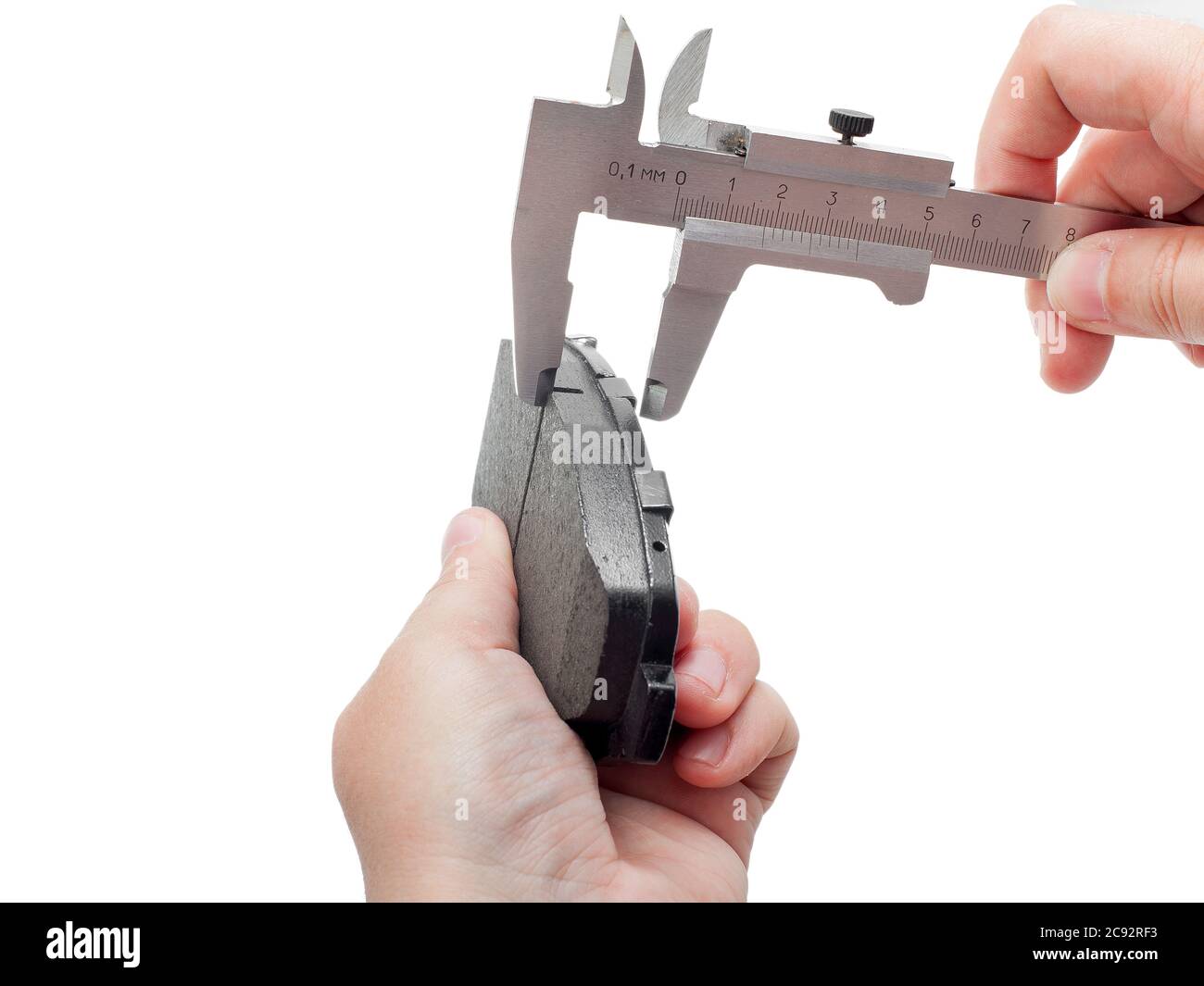Bremsbeläge des Kfz-Ersatzteiles auf weißem Hintergrund, Messung durch einen Bremssattel der Dicke auf der Hand des Ingenieurs. Stockfoto