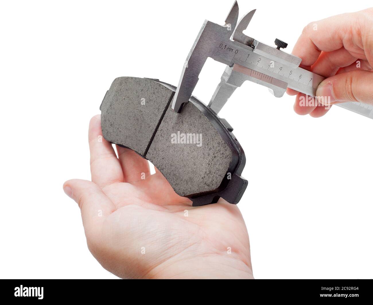 Bremsbeläge des Kfz-Ersatzteiles auf weißem Hintergrund, Messung durch einen Bremssattel der Dicke auf der Hand des Ingenieurs. Stockfoto