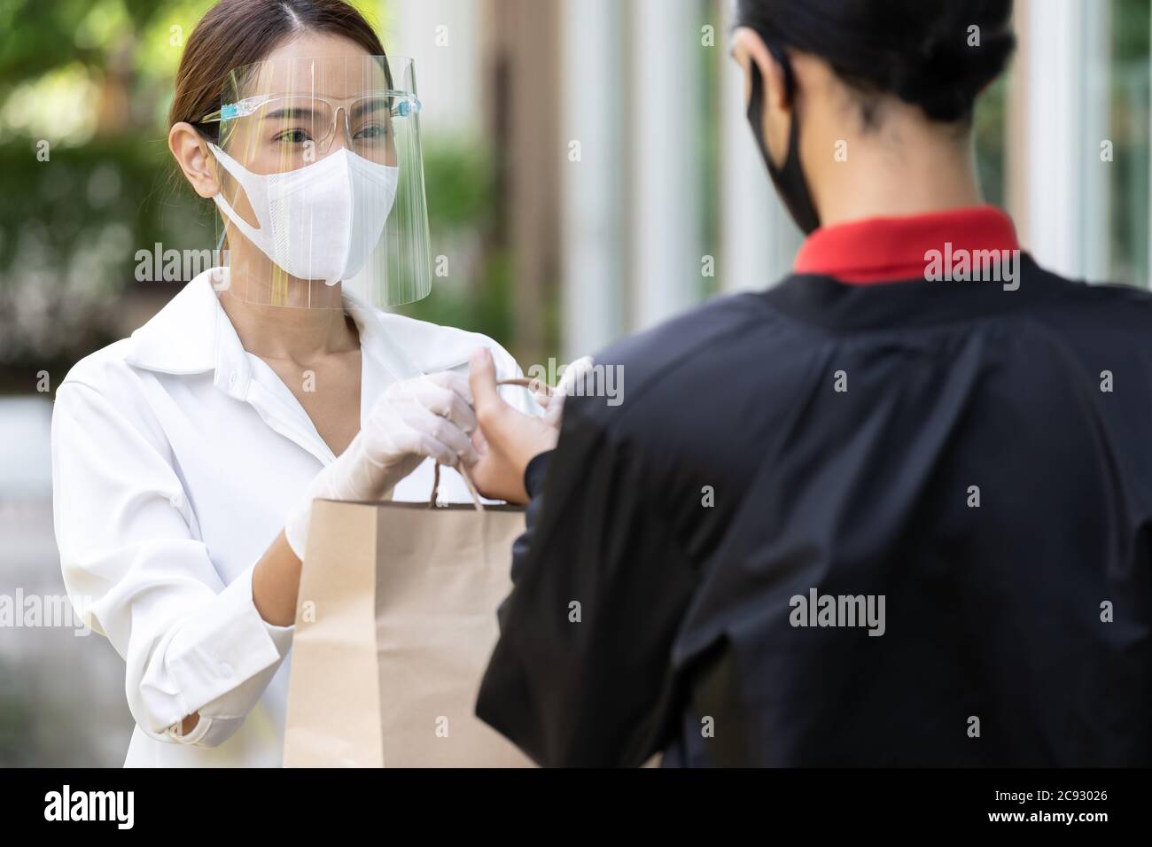 Portrait der atractive asiatische Frau geben Bäckerei Lebensmittelgeschäft Tasche zu liefern Mann, um es an Kunden zu liefern Online-Bestellung zu machen. Konzept für den Lieferservice Stockfoto