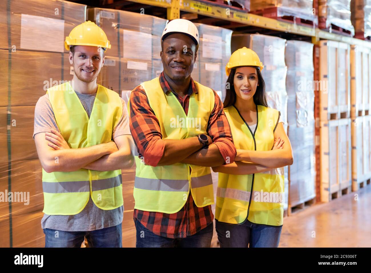 Portrait african Black Warehouse Supervisor stehen und kreuzten seine Arme mit seinem interracial Team in großen Lager-Distributionszentrum. Business-Ware Stockfoto