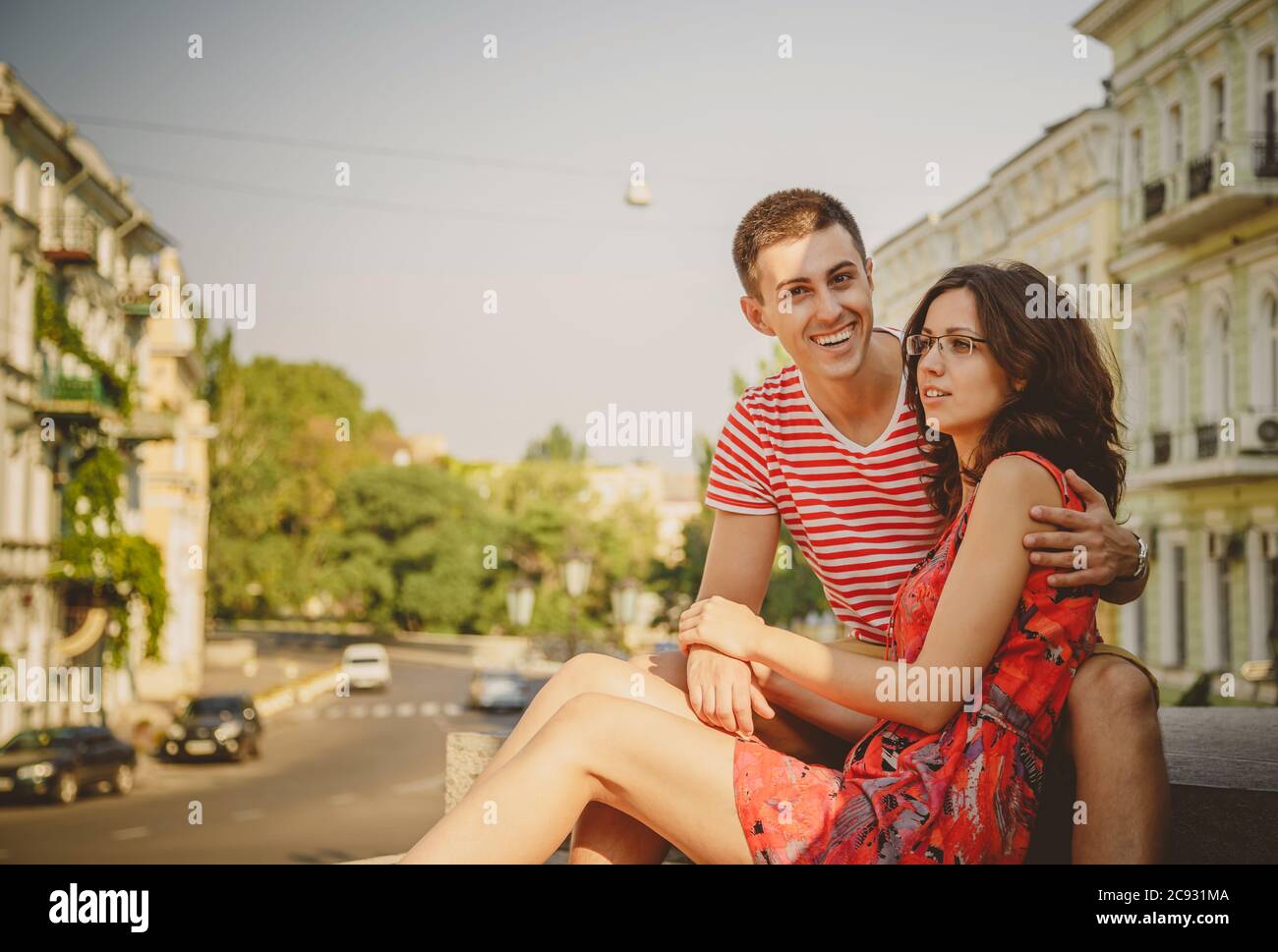 Nette junge lächelnde Paar in der Liebe umarmt, sitzen im Freien an der grünen Stadt Straße, Sommer. Mädchen trägt Brille von ihrem Freund Stockfoto