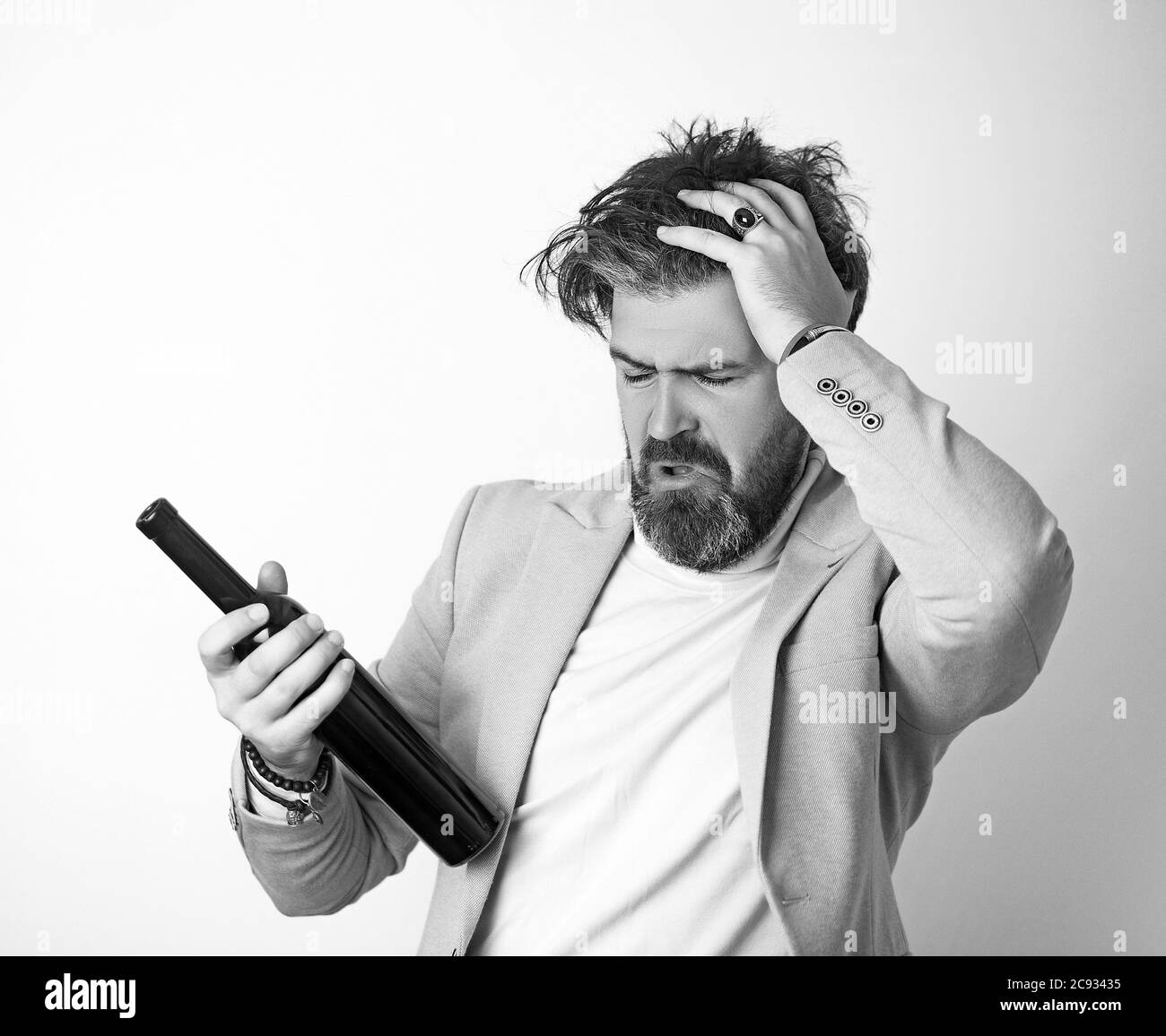 Mann mit grauen Haaren und Bart mit Alkohol trägt blaue Jacke. Stockfoto
