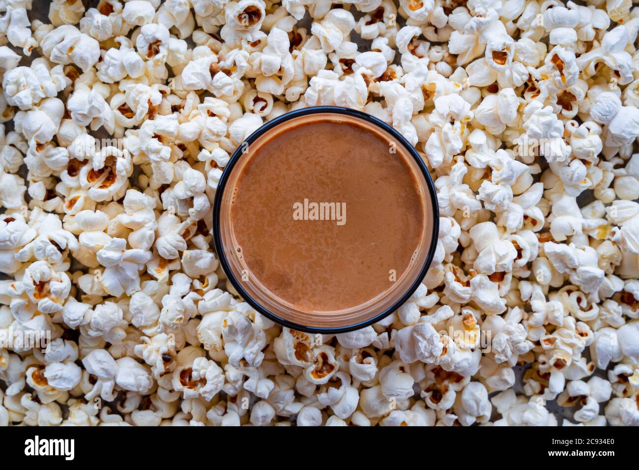 Draufsicht auf eine Tasse Tee im Hintergrund von hausgemachten Popcorns platziert. Hausgemachter Snack. Stockfoto