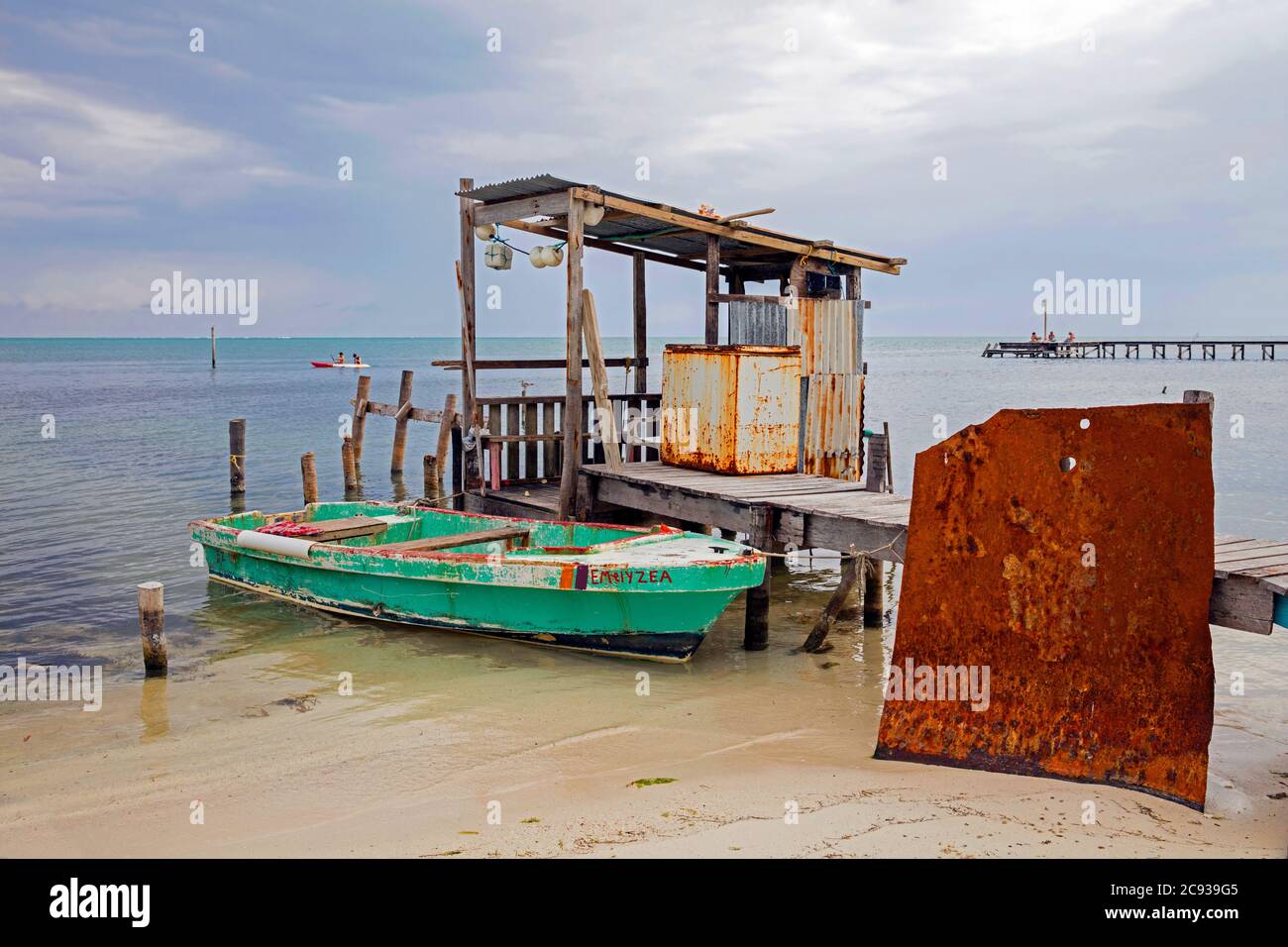 Kleines Fischerboot am Strand und alter Holzsteg auf Caye Caulker / Cayo Caulker, Koralleninsel vor der Küste von Belize in der Karibik Stockfoto