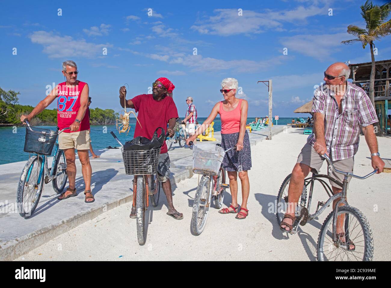 Heimischer schwarzer Mann, der älteren westlichen Touristen auf Caye Caulker / Cayo Caulker, Insel in der Karibik, Belize, stacheligen Hummer zeigt Stockfoto