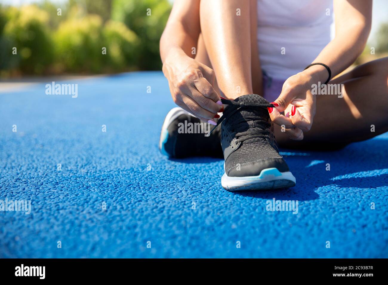 Nahaufnahme einer Sportlerin, die ihre Schnürsenkel vor dem Laufen bindet. Leerzeichen für Text. Selektiver Fokus. Konzept von Sport und gesundes Leben. Stockfoto