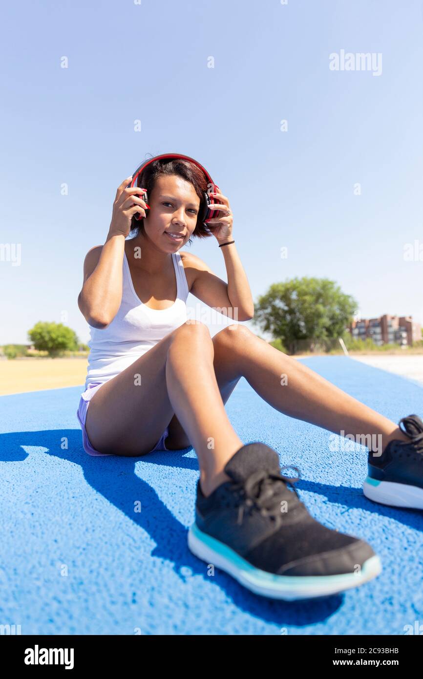 Sportliche Mädchen sitzt auf dem Boden trägt Kopfhörer. Leerzeichen für Text. Lifestyle- und Sportkonzept. Stockfoto