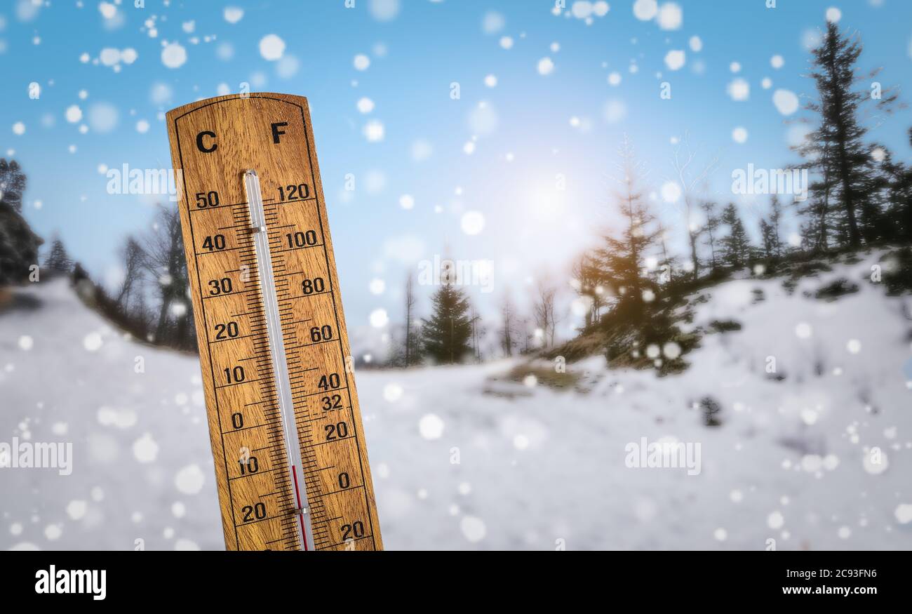 Holzthermometer vor einer verschneiten Winterlandschaft Hintergrund. Kalte Temperaturen mit extremem Winterwetterkonzept. Stockfoto