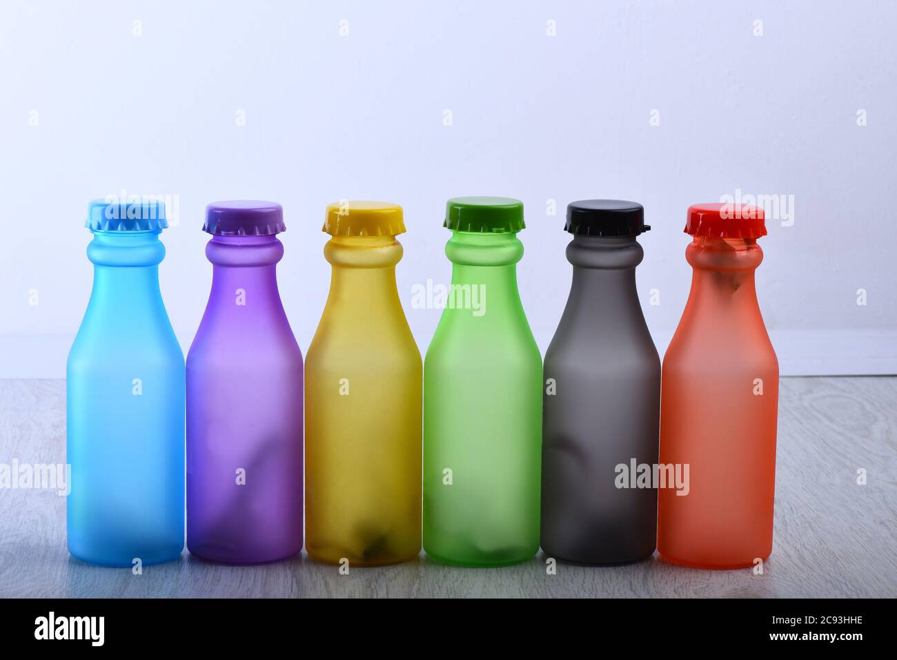 Set von Flaschen in verschiedenen Farben. Reihe von bunten alkoholfreien Getränken auf hellgrauem Hintergrund. Regenbogen Komposition und Getränkekonzept. Energy Drinks Behälter mit verschiedenen Geschmacksrichtungen auf Holztisch Stockfoto