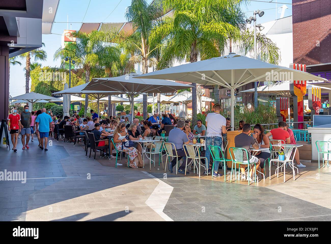 Punta Umbria, Huelva, Spanien - 3. Juni 2020: Huelva, Spanien - 27. Juli 2020: Menschen, die auf der Terrasse eines Cafés und einer Bar im Einkaufszentrum Holea sitzen. Einige Stockfoto