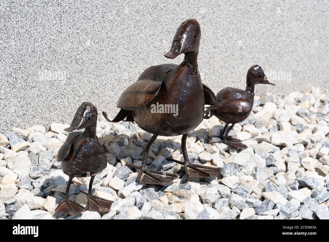 Eine Mumie und zwei Baby Ente dekorative Kunst Skulpturen aus recyceltem Metall stehend auf Steinen in einem Garten, Großbritannien Stockfoto