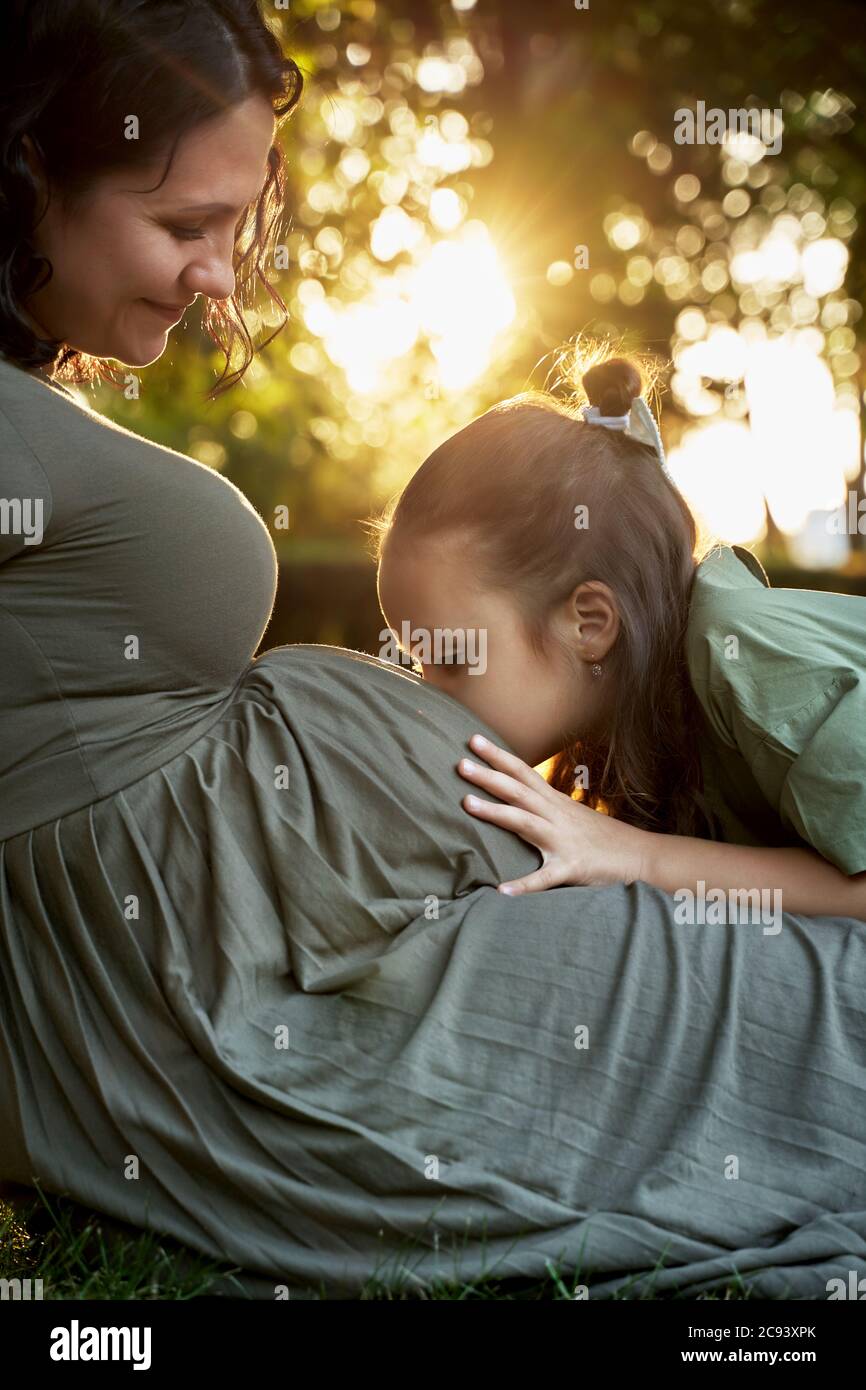 Kleines Mädchen küsst den Bauch ihrer schwangeren Mutter Stockfoto