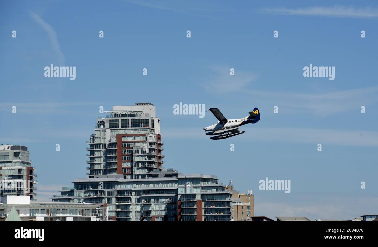 Ein Harbor Air Wasserflugzeug kommt für eine Landung im Binnenhafen vor Wohnheimen in Victoria, British Columbia, Kanada auf Vanco Stockfoto