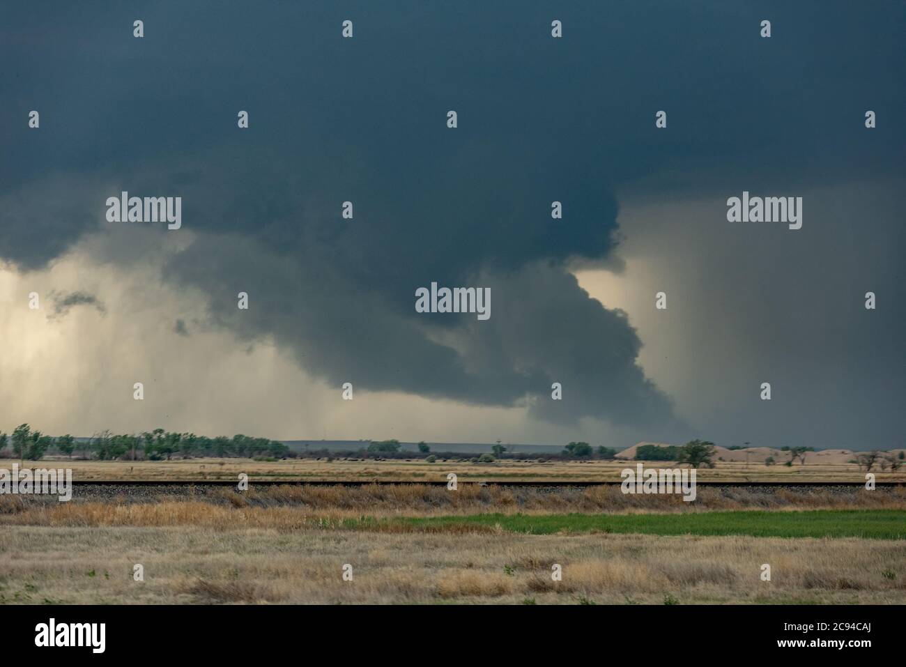 Ein riesiger Tornado bewegt sich schnell entlang einer Autobahn in Richtung einer Stadt Meilen vor. Stockfoto
