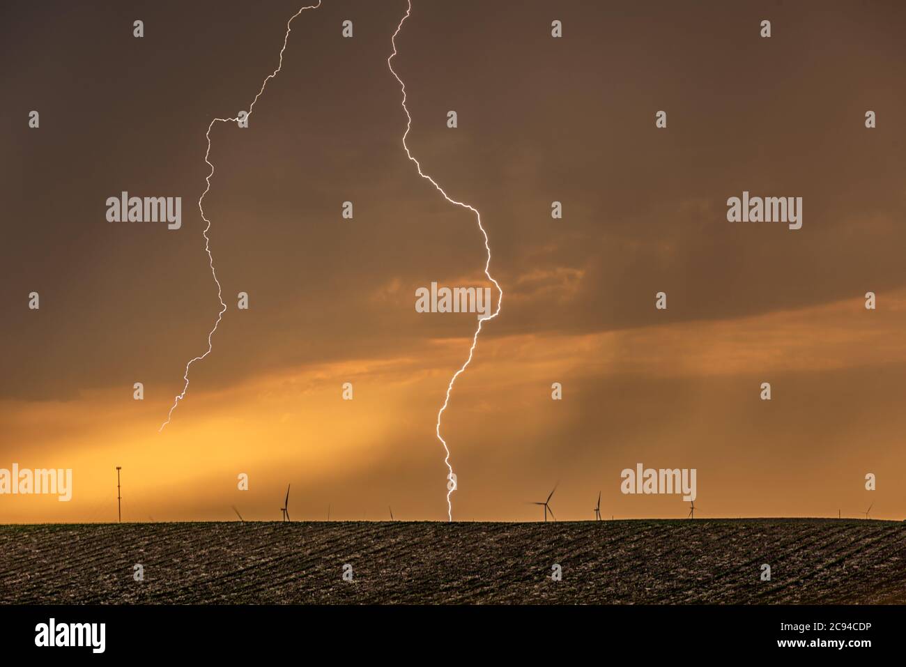 Ein Gewitter bei Sonnenuntergang passiert die Great Plains, während strömender Regen und knackende Blitze den Horizont markieren. Stockfoto