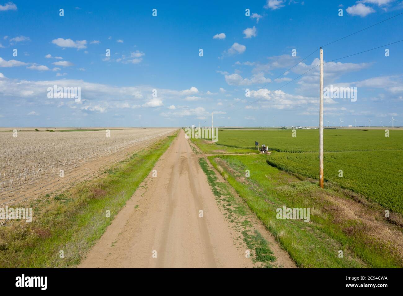 Ein Drohnenbild einer klassischen Backcountry-Schotterstraße im Mittleren Westen mit einer Perspektive auf die Straße, die ins nichts führt. Stockfoto