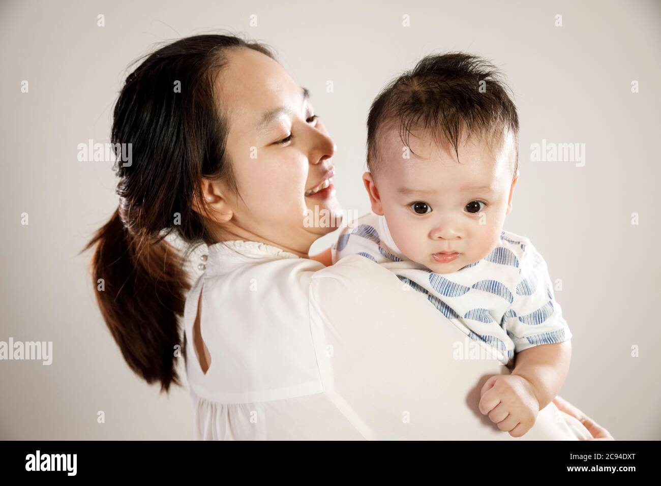 Asiatische Mutter hält Baby Sohn Porträt, glücklich vietnamesischen Eltern mit Kleinkind Kind Blick über die Schulter, weißer Hintergrund Stockfoto