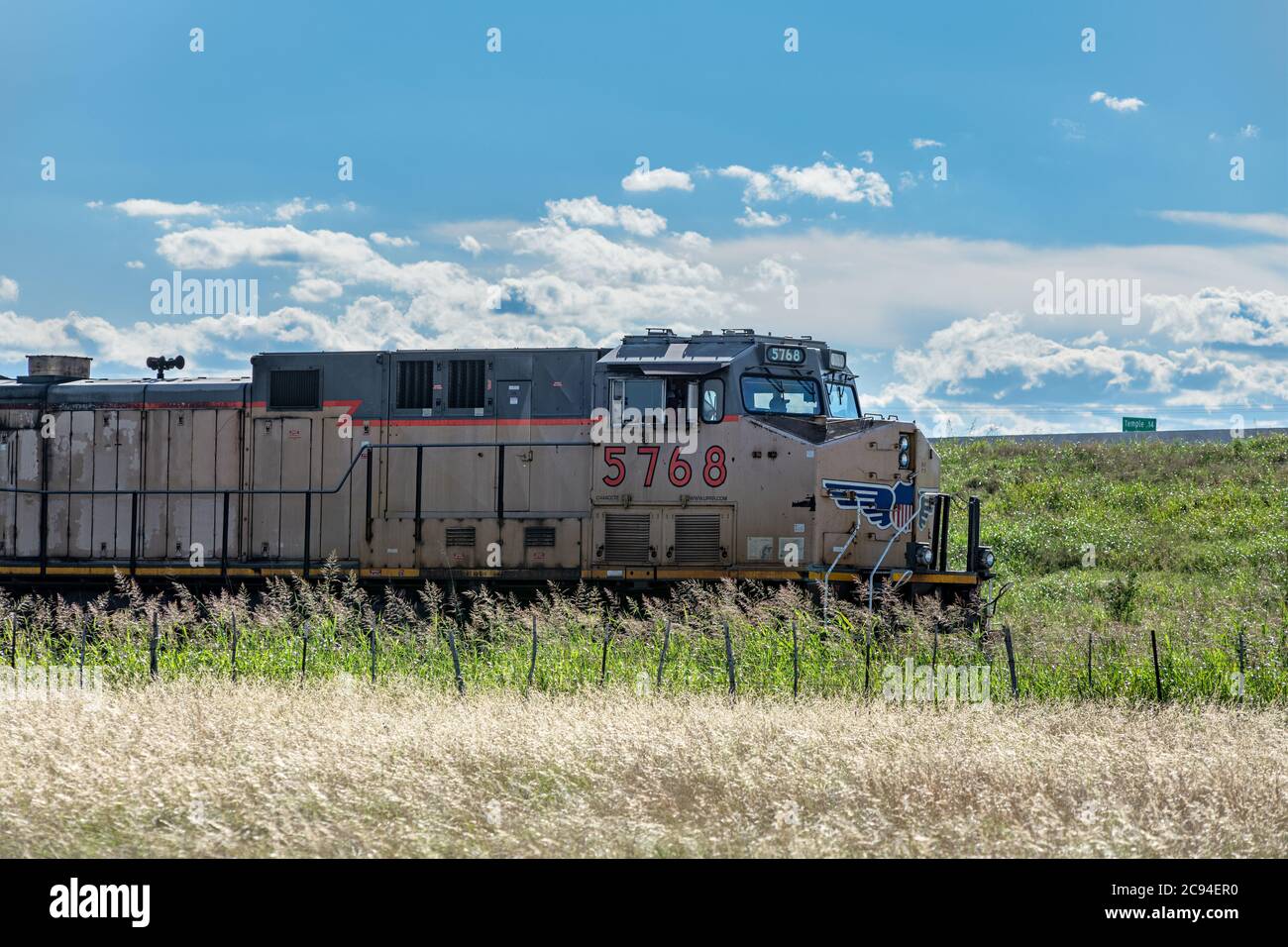 Ein Zug fährt durch einen ländlichen Teil von Texas und zieht eine Flotte von Lastautos dahinter. Stockfoto