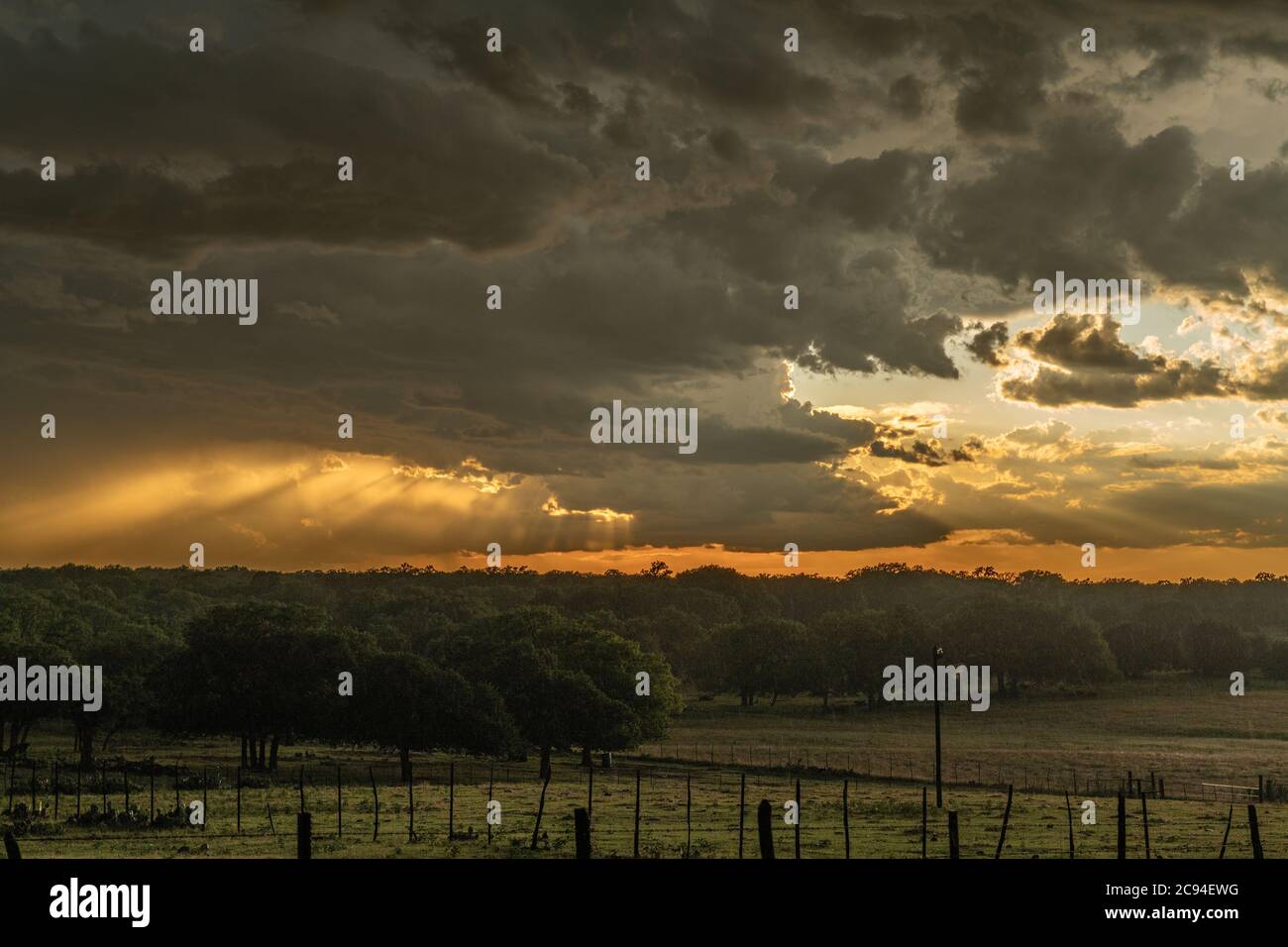 Weite Perspektive eines massiven Mesocyclone Wetter supercell mit der untergehenden Sonne durchbohrt die Wolken zu schönen niedrigen Lichtstrahlen zu bilden. Stockfoto