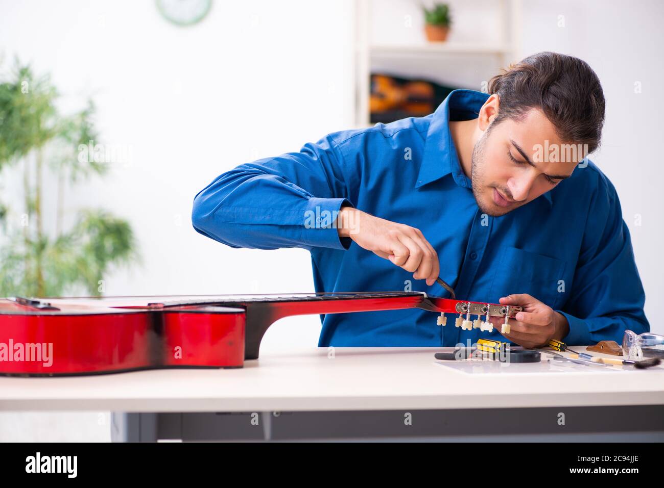Junger Mann Reparatur der Gitarre Stockfoto